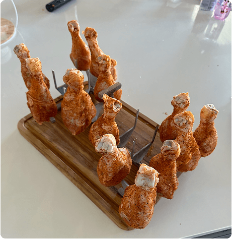 Raw chicken wings placed on cooking rack pins